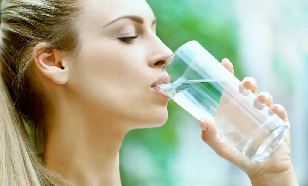 Frau trinkt klares Wasser – Symbol für gesundes Wasser.